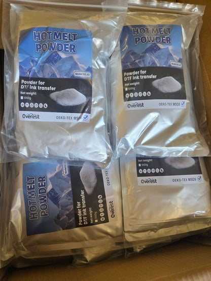 Four sealed bags of Overest Hot Melt Powder for DTF ink transfer arranged on a brown cardboard surface. Each bag contains white powder and has a blue-and-black label with the Overest branding.